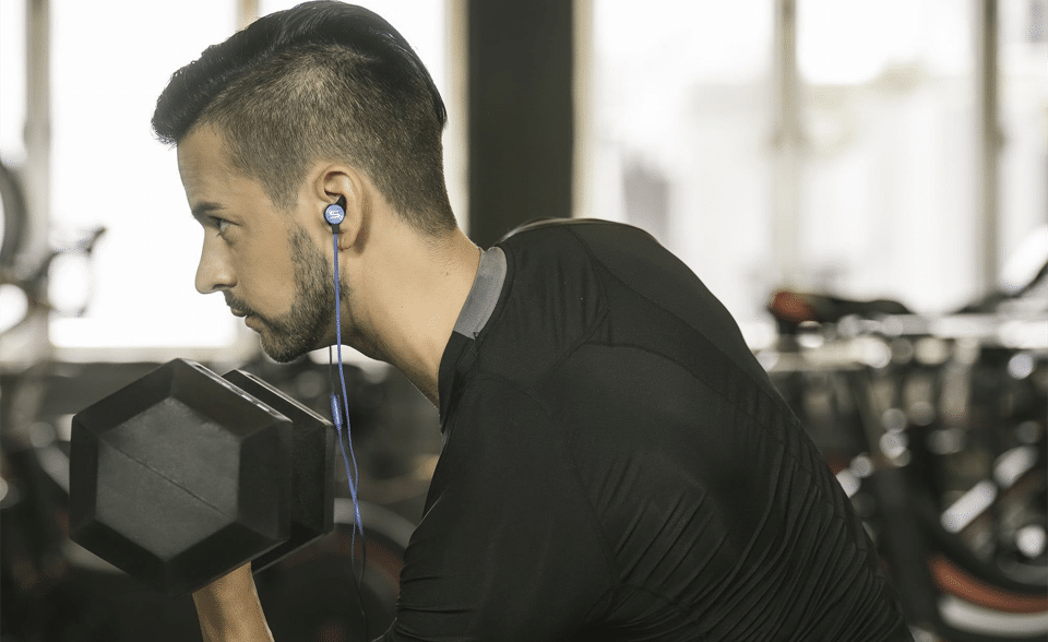 Bărbat cu căști în urechi la sala de fitness.