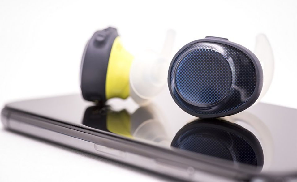Casti in-ear albastru cu galben pe un telefon.